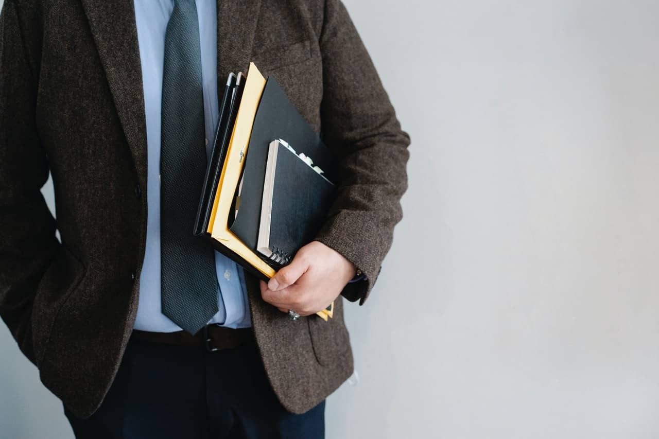 A man wearing a suit holding books in his left hand